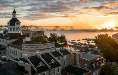the sunrise over the water in Kingston, with the top of City Hall and other buildings downtown taking up the bottom and left side of the frame.