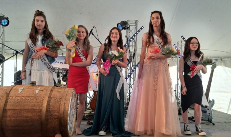Cinq adolescentes en robe tenant un bouquet de fleurs à la main sur une scène pendant le couronnement de la duchesse