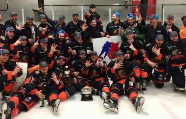 Équipe de hockey après une victoire de championnat, les joueurs portent un uniforme noir et orange.