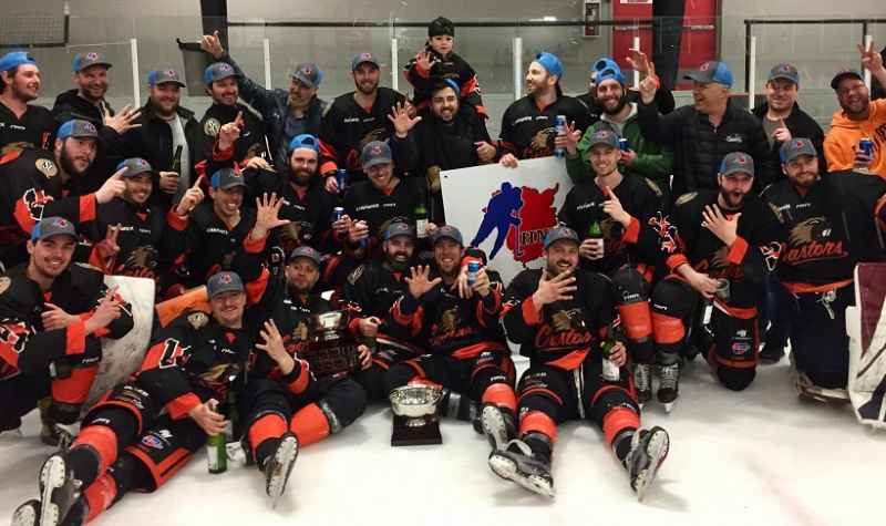 Équipe de hockey après une victoire de championnat, les joueurs portent un uniforme noir et orange.