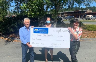 A man and two women hold a large cheque for $3,000.