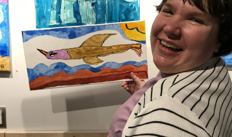 A woman showing her colourful painting of a fish