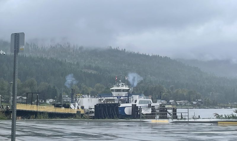 A docked ferry with mountains and lake in the background.