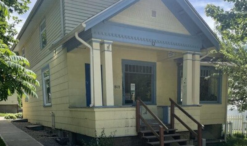 Yellow and blue building with steps leading up to the porch and front door.