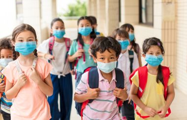 Plusieurs enfants portant le masque s'apprêtent à retourner en salle de classe.