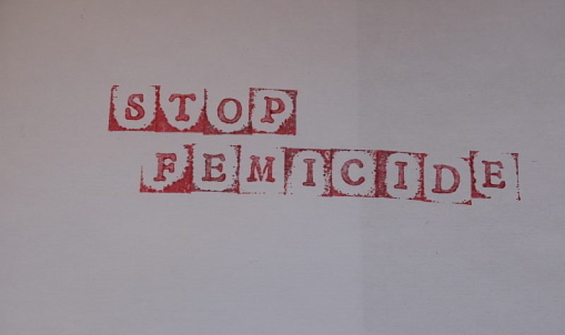 Les mots « Stop Feminide» étampés en rouge sur une feuille blanche.
