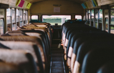 An empty bus is seen with brown and black seats on either side of an aisle.