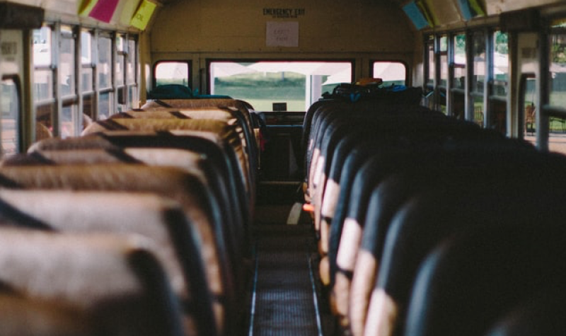 An empty bus is seen with brown and black seats on either side of an aisle.