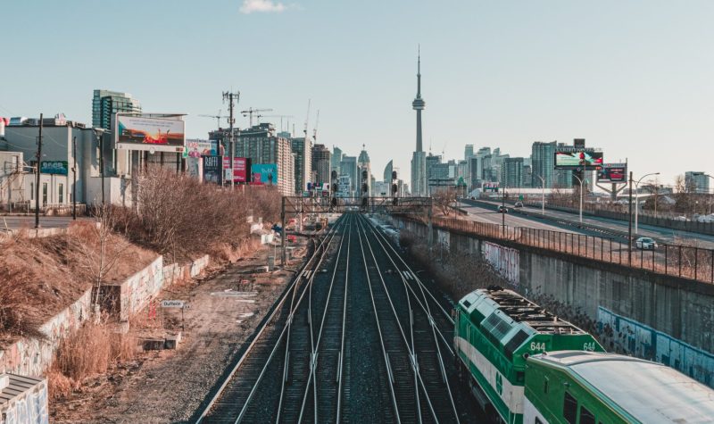 Metrolinx's GO train tracks with GO train in the foreground and CN tower in the background