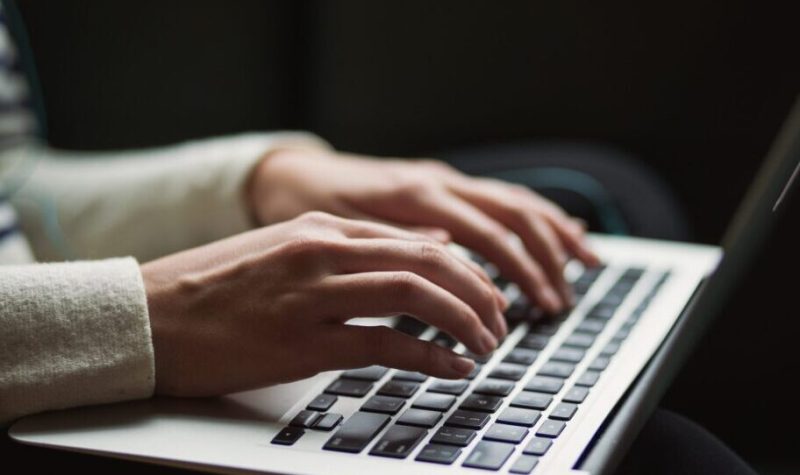 Les mains d'une femme tape sur un clavier d'ordinateur macbook de Apple.