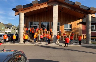 the friendship society is a building made of wood. The staff that work at the friendship society are standing in front of the building.