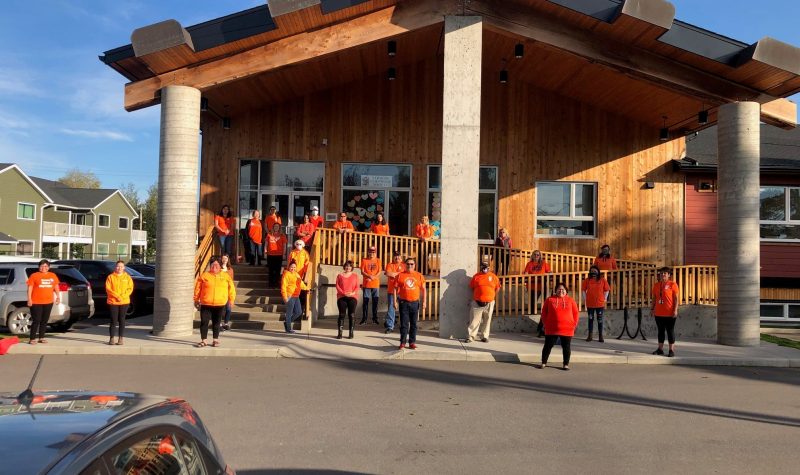 the friendship society is a building made of wood. The staff that work at the friendship society are standing in front of the building.