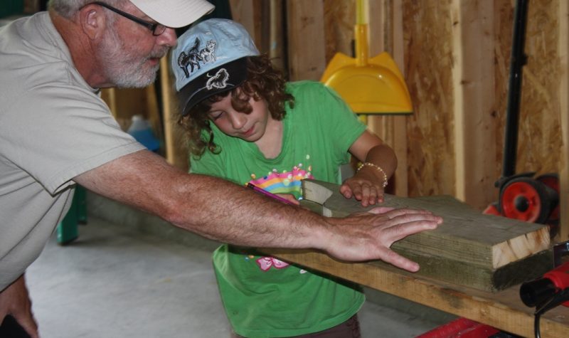 Danny and his grand-daughter are in his workshop cutting a piece of wood.