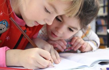 Deux enfants de jeune âge collaborent pour un travail scolaire.