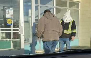 Un homme portant une capuche à la KKK devant un bureau de poste