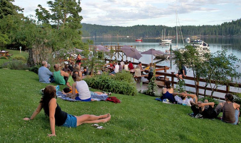 People relax on a sloping lawn facing the ocean on a rural island.