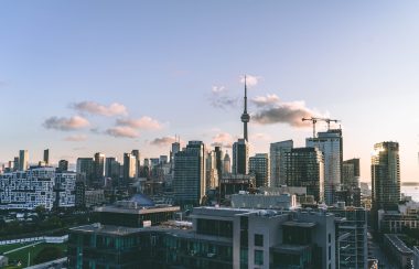 Buildings against a blue sky background with several clouds in the distance.