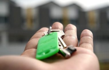 Une clé dans une main devant des maison