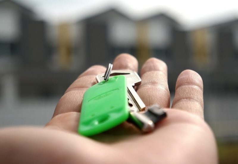 Une clé dans une main devant des maison