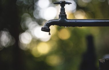 A droplet is about to fall from an outdoor water tap.