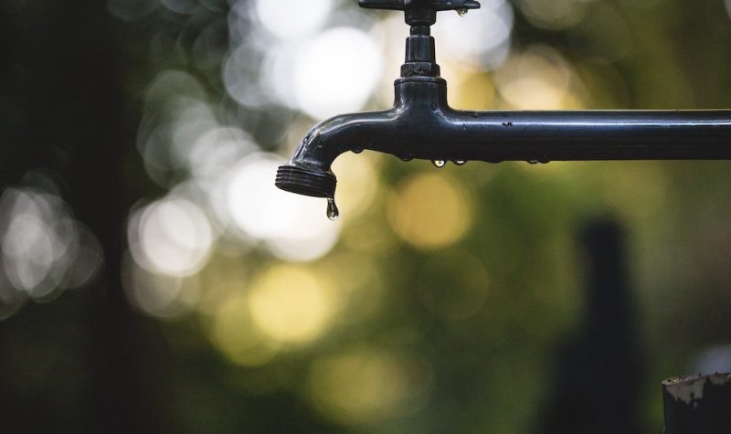 A droplet is about to fall from an outdoor water tap.