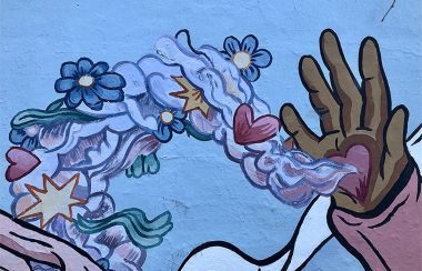 An image of a mural of a hand with a heart in its palm and flowers flowing from the heart.