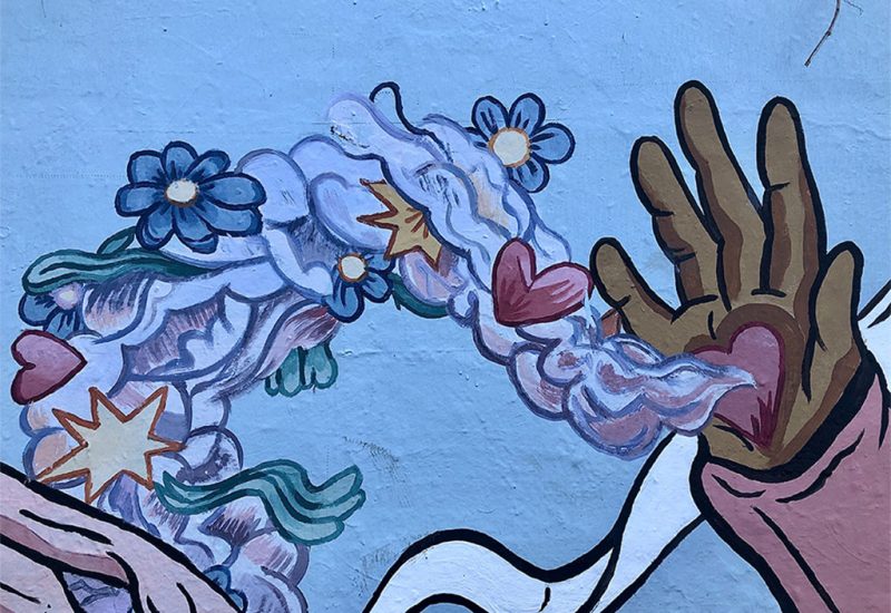 An image of a mural of a hand with a heart in its palm and flowers flowing from the heart.