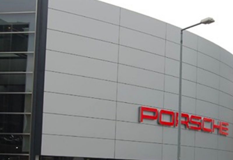 An image of the outside of a Porsche dealership. Only the gray exterior wall can be seen with letters spelling out 