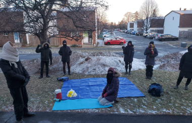 Seven protestors dressed warmly on snowy grass of a front lawn where the eviction protest took place