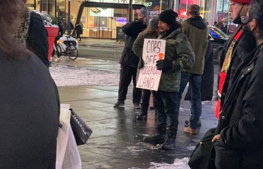 A man holding up a white sign outside in a crowd.