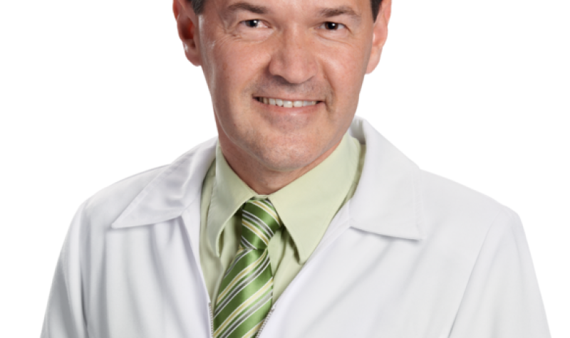 A photo of pharmacist Marc Aufranc on a blank background, wearing a white lab coat and a green shirt and tie.