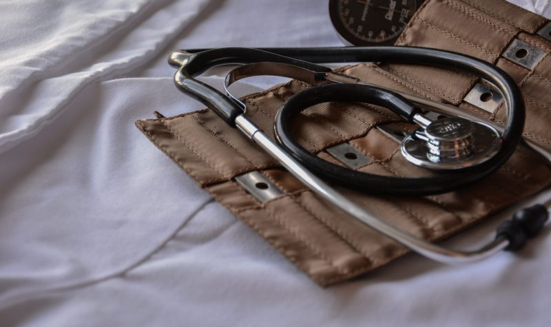 A stethoscope lies atop a leather case and white sheet.