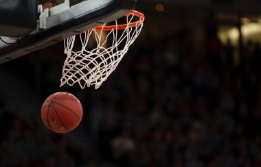 A basketball goes through a net on a court.