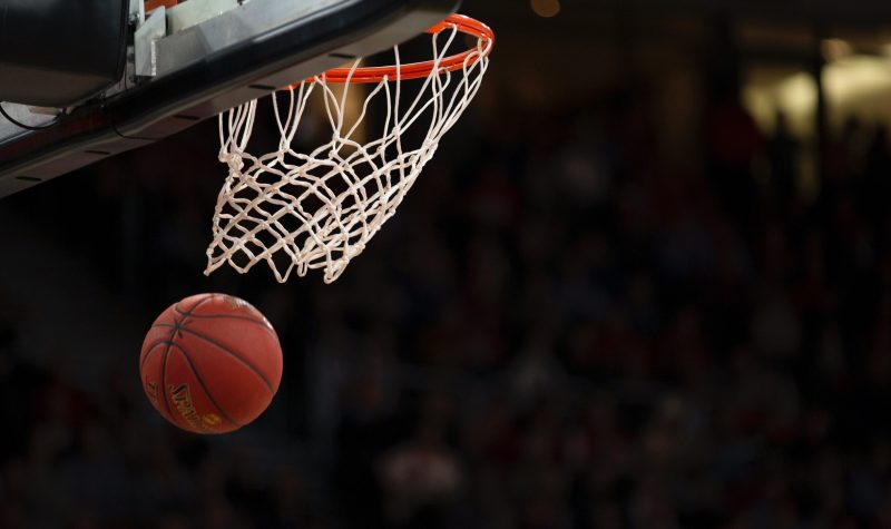 A basketball goes through a net on a court.