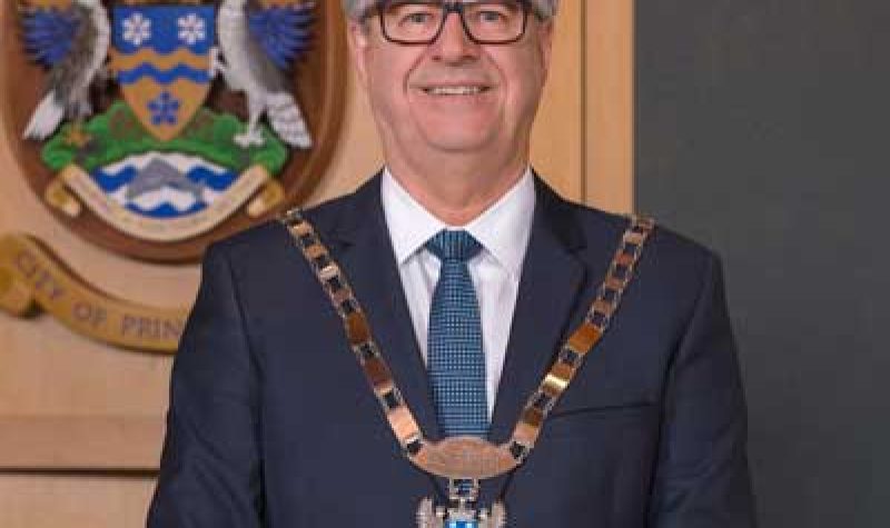 An image of Mayor Lyn Hall standing in front of the City of Prince George crest.