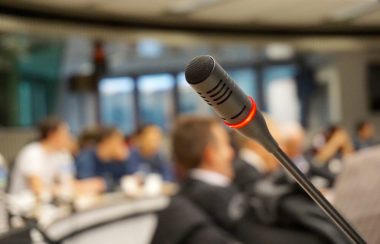 Un microphone en avant-plan et une petite foule hors champ en arrière-plan