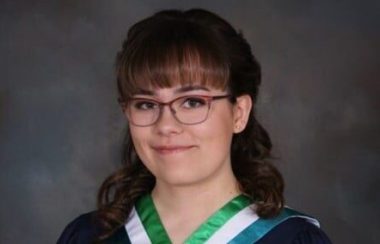 Jeune femme portant une toge de graduation avec roses rouges