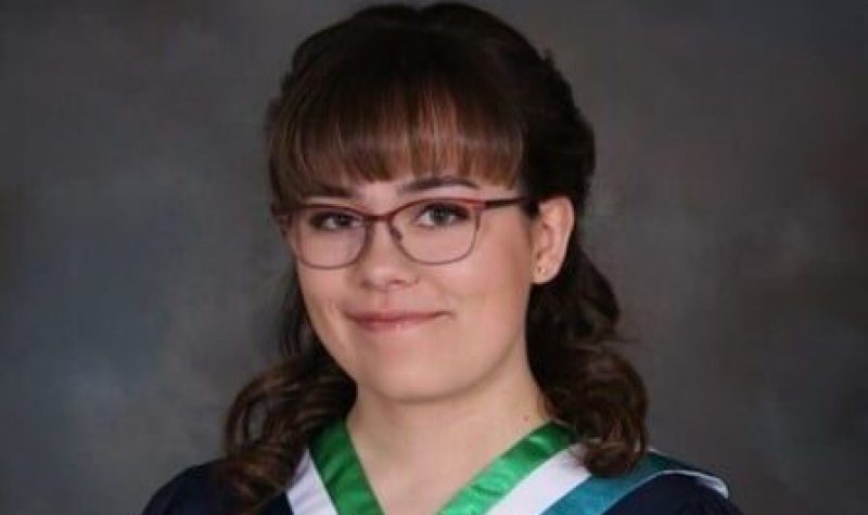 Jeune femme portant une toge de graduation avec roses rouges