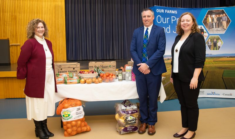 Photo of Janet Simm, CEO & President of Northwood, Agriculture Minister Greg Morrow, and Letitia Rowley from Gordon Food Services. There is a table of produce behind them. They are all standing and smiling for the camera.