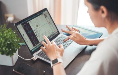 Une femme de profil tape sur le clavier d'un ordinateur portable.