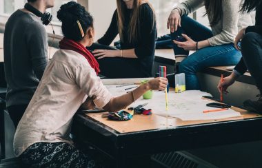 Des personnes avec des crayons autour d'une table assis sur un divan