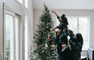 Une famille fait la décoration de leur arbre de Noël.