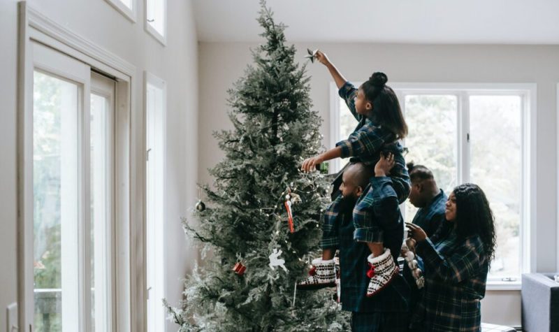 Une famille fait la décoration de leur arbre de Noël.