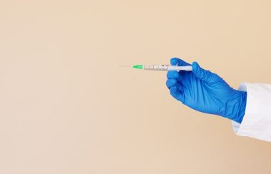 Une main gantée tend un vaccin