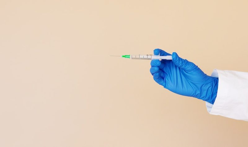 Une main gantée tend un vaccin