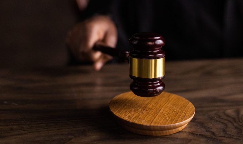 A stock photo of a hand slamming a courtroom gavel on a wooden table
