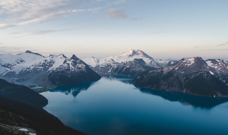 A wide shot of BC glaciers, with a blue lake in the foreground