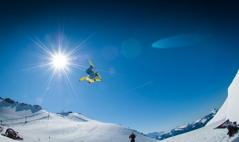 A snowboarder performs a jump, caught in this photo mid air against a blue sky