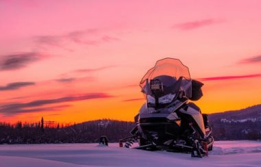 Moto neige avec un coucher de soleil en arrière plan.