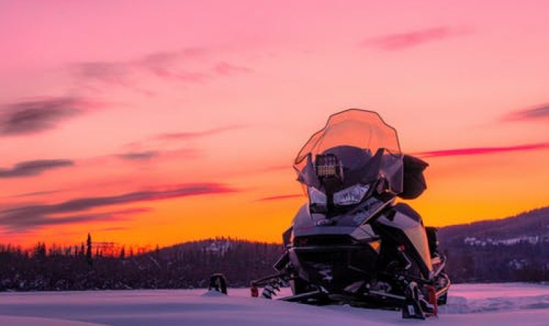 Moto neige avec un coucher de soleil en arrière plan.
